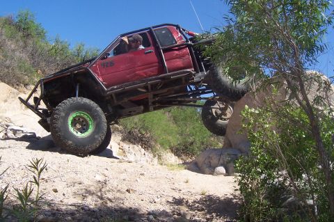 1981 Ford F-150 - This heavily modified truck is navigating a difficult rocky terrain on a sunny day.
