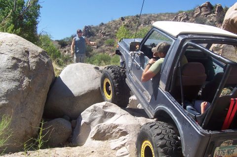 1981 Ford F-150 - An off-road vehicle maneuvers through a challenging rocky landscape under a clear blue sky.