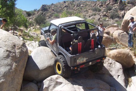 1981 Ford F-150 - Off-road vehicle carefully maneuvers through a rocky terrain with spectators present.