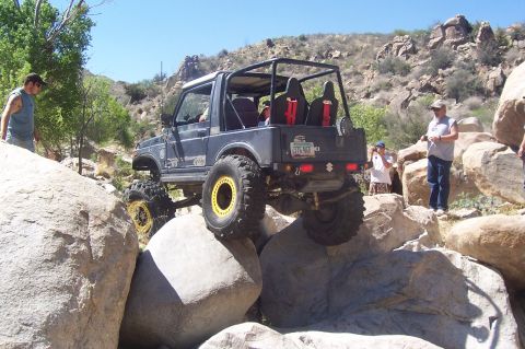 1981 Ford F-150 - A modified Suzuki Samurai navigates a rocky trail with spectators observing the off-road action.