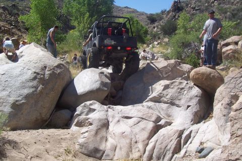 1981 Ford F-150 - A group of people watch an off-road vehicle traverse a challenging rocky path.
