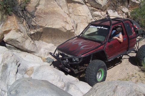 1981 Ford F-150 - Customized off-road truck with extensive modifications tackles a challenging rocky trail.
