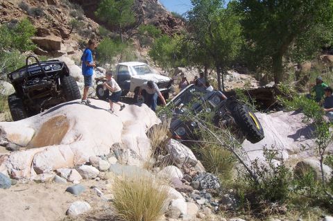 1981 Ford F-150 - Several off-road vehicles are seen in a rocky, natural environment, with one vehicle tipped on its side.