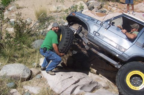 1981 Ford F-150 - Off-road vehicle encounters difficulty on rocky terrain, requiring assistance with a spare tire.