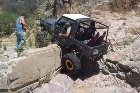 1981 Ford F-150 - Off-road vehicle carefully maneuvers over rough, rocky terrain with assistance from a spotter.