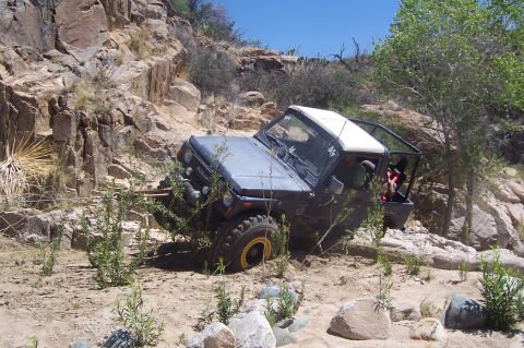 1981 Ford F-150 - Suzuki Samurai navigating a challenging off-road course in a rocky, arid environment.