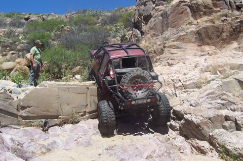 1981 Ford F-150 - A modified off-road vehicle attempts to climb over rocks on a steep incline.