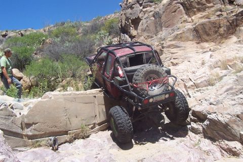 1981 Ford F-150 - Off-road pickup truck navigating a rocky incline with a man observing the action.