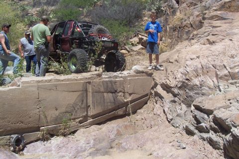 1981 Ford F-150 - A heavily modified pickup truck navigates a challenging off-road obstacle with onlookers present.