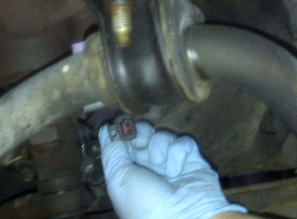 Hand holding electrical connector near suspension component