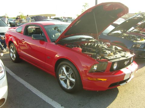 2007 Ford Mustang - Red 2007 Ford Mustang at a car show, hood up to display the engine.