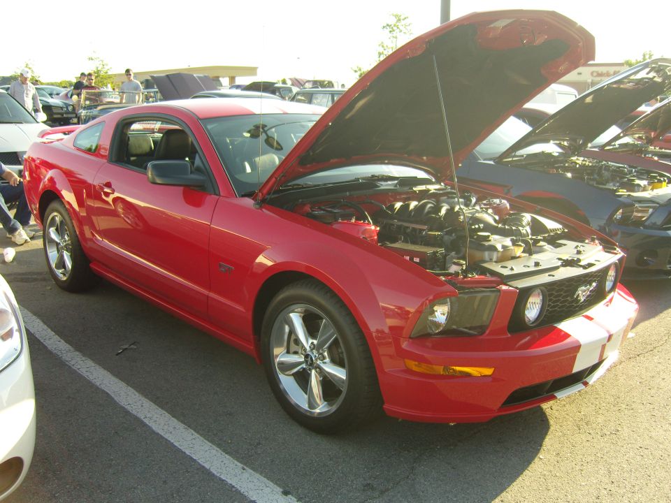 Red 2007 Ford Mustang parked with hood open, showing engine. Another car is visible behind it