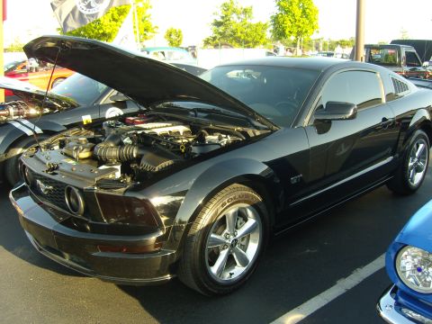 2007 Ford Mustang - Black 2007 Ford Mustang GT at a car show, hood open to display the engine.