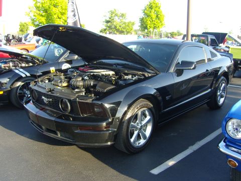 2007 Ford Mustang - A black Ford Mustang GT is parked with its hood open, showing the engine bay.