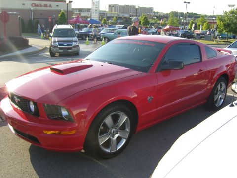 2007 Ford Mustang - A red Ford Mustang coupe is parked at an outdoor event. A banner on the windshield reads "2005 Mustang Drag Racing".