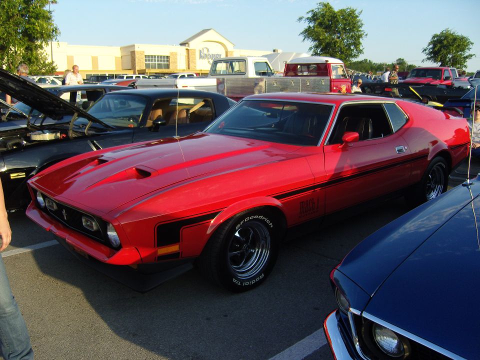 Red 1971 Ford Mustang Mach 1 with black side stripes and hood scoops, parked in a lot