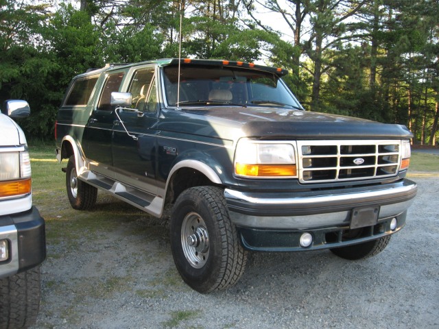 Dark green SUV, 3/4 front view, with chrome trim and running boards
