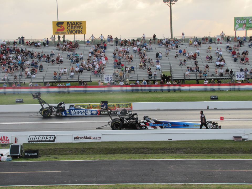 Two drag racing cars on a track, one blue with white and red stripes, the other blue and white with 'MATCO TOOLS' branding