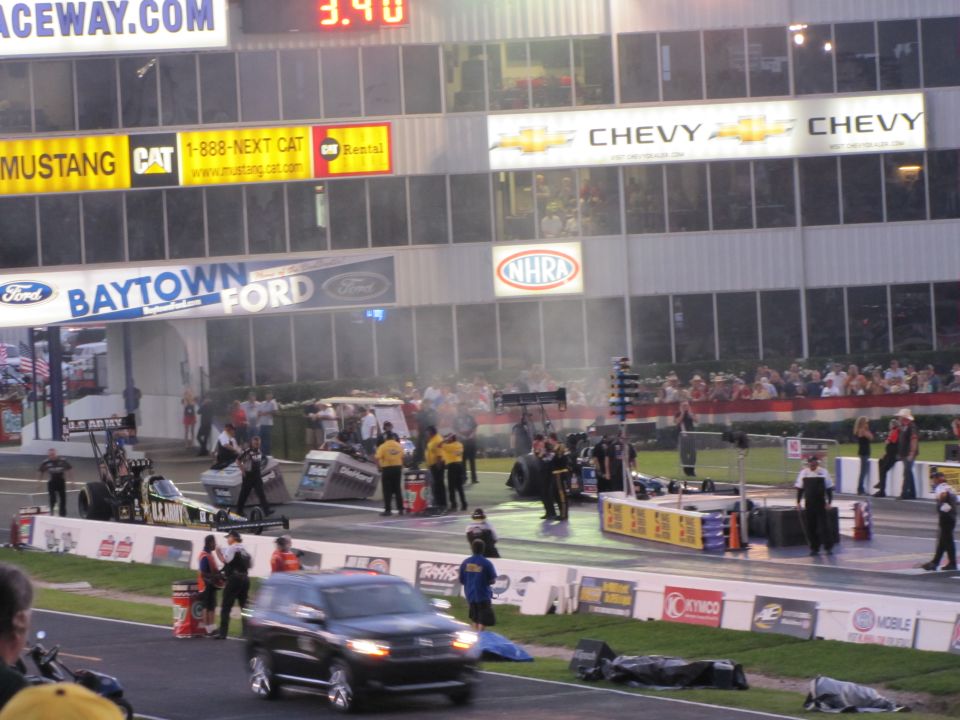 drag strip with dragsters, support vehicles, and spectators