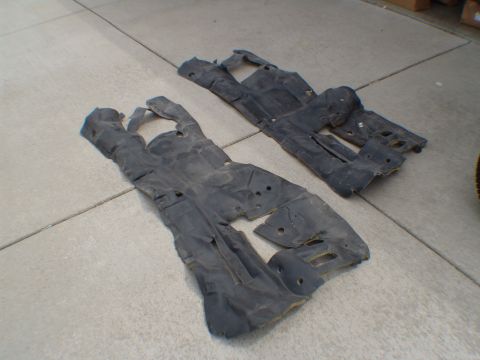 1996 Ford Bronco - Two black plastic underbody shields are laid out on a concrete surface.
