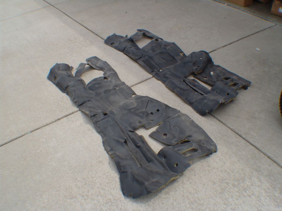 two black plastic underbody shields on concrete