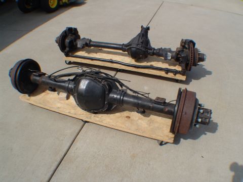 1996 Ford Bronco - Two vehicle rear axles are displayed on wooden dollies on a concrete surface.