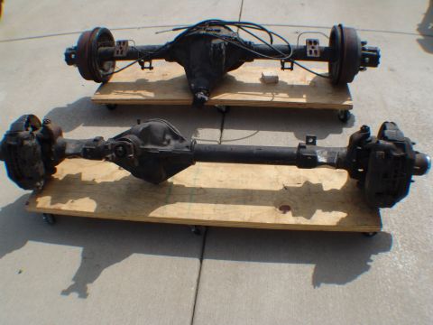 1996 Ford Bronco - Two rear axles, one equipped with drum brakes and the other with disc brakes, are presented on wooden dollies.