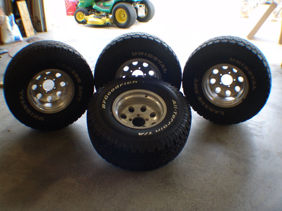Four BFGoodrich All-Terrain T/A and Uniroyal tires mounted on aluminum alloy wheels