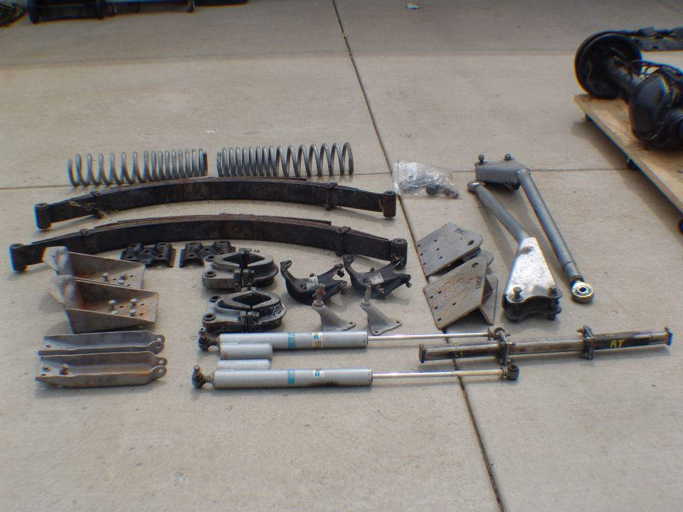 Collection of suspension parts including leaf springs, shocks, and brackets