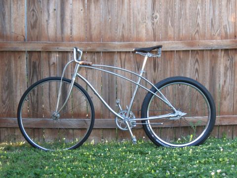 1994 Ford Bronco - A custom cruiser bicycle with a chrome frame and black tires sits on the grass against a weathered wooden fence.