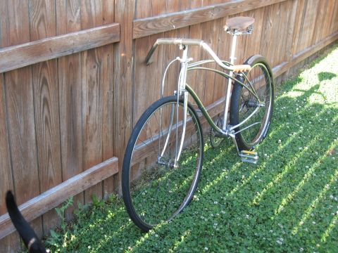 1994 Ford Bronco - A vintage cruiser bicycle with a brown leather seat is parked next to a weathered wooden fence.
