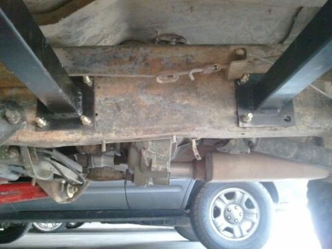 1982 Ford Bronco - The underside of a vehicle shows aftermarket frame modifications and a glimpse of another vehicle below.