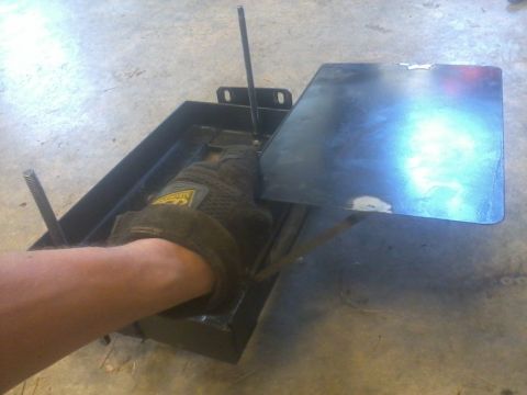 1995 Ford F-150 - A gloved hand is shown adjusting a dual battery tray with an isolator. The tray has two threaded rods.
