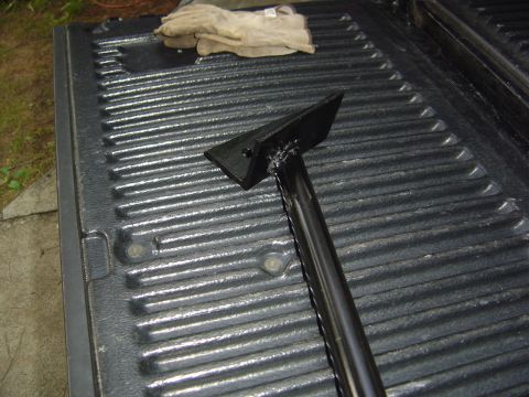 1986 Ford Bronco - A metal tool and work gloves rest on the textured surface of a truck bed.