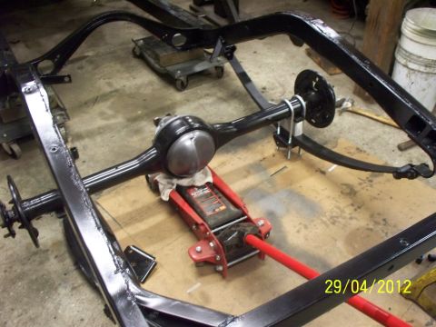1990 Ford Bronco - Vehicle frame and rear axle assembly are black. A red jack supports the rear axle.