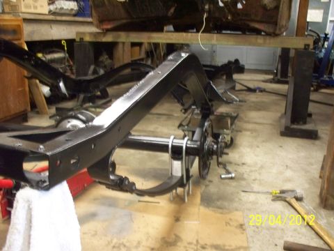1990 Ford Bronco - The vehicle's frame and suspension are disassembled and undergoing work in a garage setting.