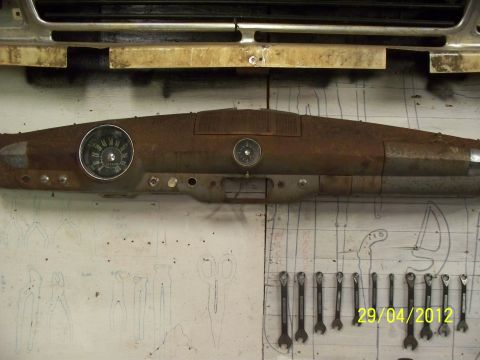 1990 Ford Bronco - A heavily rusted dashboard assembly, likely from an older vehicle, is displayed against a wall with tool outlines.