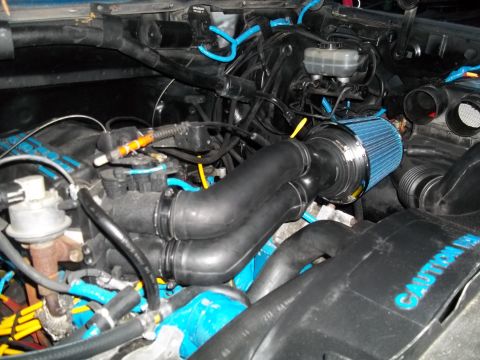 1989 Ford Bronco - Close-up of an engine bay a blue cone air filter and custom intake piping.