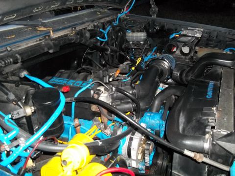 1989 Ford Bronco - Engine bay modifications with custom blue hoses and an aftermarket cold air intake system.