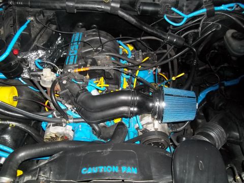 1989 Ford Bronco - Engine bay features a cold air intake and vibrant blue and yellow accents, with a "CAUTION FAN" warning visible.