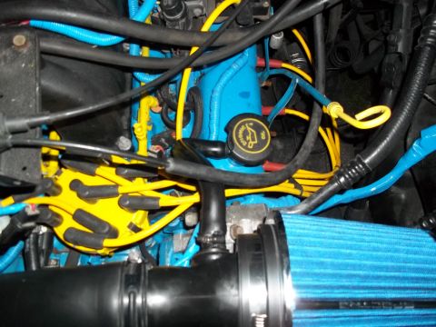 1989 Ford Bronco - Close-up of a vehicle's engine bay, custom blue and yellow wiring and a blue air filter.