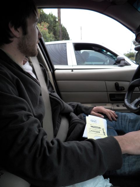 2003 Ford Crown Victoria - Passenger holds car show entry flyers inside a tan-interior sedan with manual window switches.