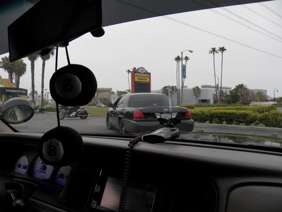 View from inside car of black Crown Victoria ahead near Knotts Berry Farm and Starbucks signs