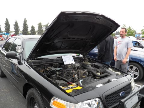 2003 Ford Crown Victoria - black Crown Victoria sits with hood raised, its V8 engine bay on display at a show.