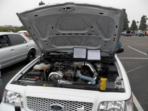 2003 Ford Crown Victoria - Modified Ford engine compartment showing a turbo setup and display placards at a car show.