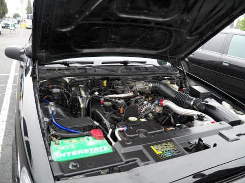 2003 Ford Crown Victoria - Engine compartment of a Ford showing a green Interstate battery and routed coolant lines.