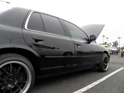 2003 Ford Crown Victoria - Glossy black Crown Vic side view showing tinted windows, body molding and staggered wheels