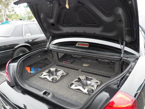2003 Ford Crown Victoria - Sedan trunk audio install showing twin subwoofers in a fabricated box, black Crown Victoria parked nearby