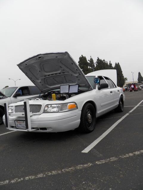 2003 Ford Crown Victoria - Three-quarter view of white Crown Victoria with raised hood and front push bar, California plate visible