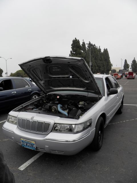 2003 Ford Crown Victoria - Three-quarter front of silver Mercury, hood open over engine with blue hose, DEWGONG vanity plate